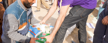 رجل يعطي رجل أخر غذاء  وهم مبتسمين